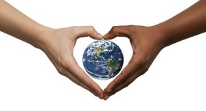 Two hands, one light and one dark, forming a heart shape around a globe representing Earth.